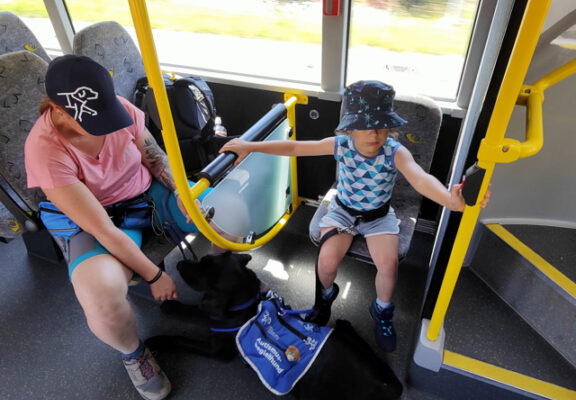 Autismusbegleithund mit Kind und Mutter im Bus.